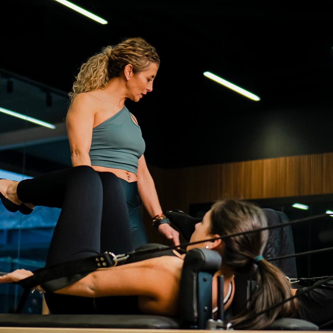 Instructora guiando a una alumna sobre el Reformer en Moris